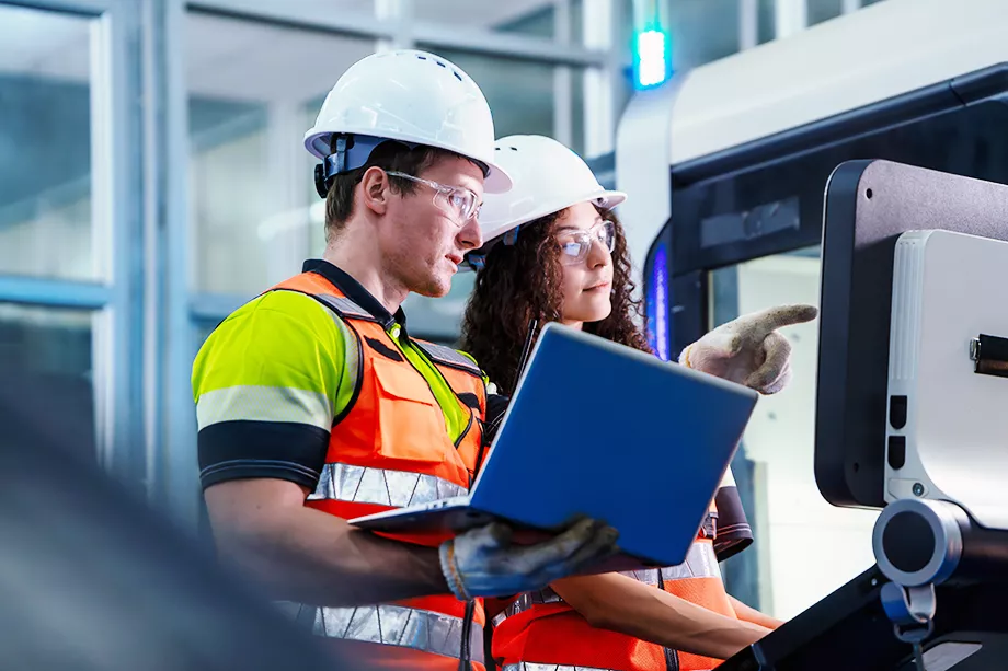 Two people are looking at a laptop computer. Concept of Industry 4.0 with diverse engineers collaborating on automation technology.