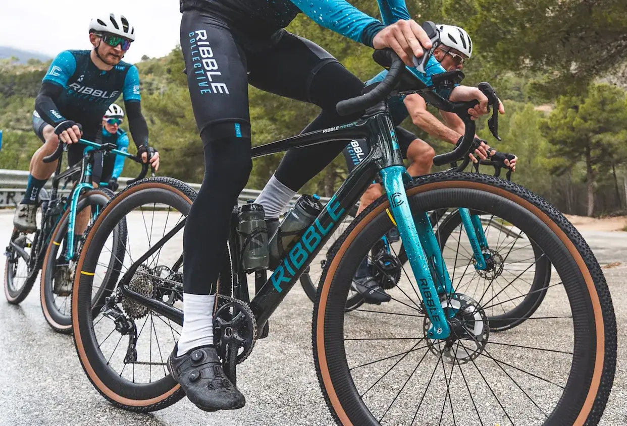 Group of cyclists riding Ribble road bikes on a scenic mountain road wearing Ribble Collective team kits